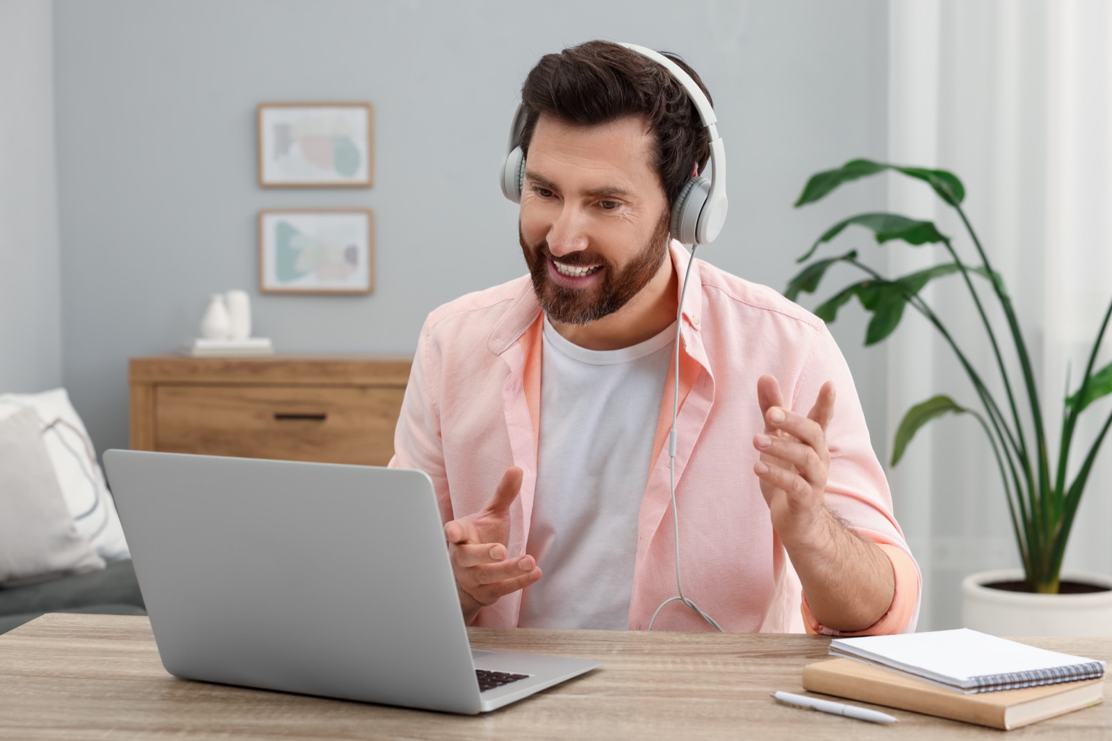 Mężczyzna w słuchawkach uczestniczący w spotkaniu online przy laptopie